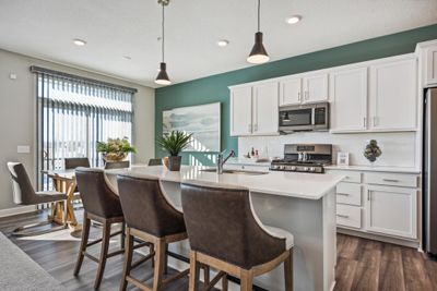 (Photo of a decorated model, actual homes finishes will vary) The spacious kitchen features a large center island, quartz countertops, LVP floors, stainless appliances and more! | Image 2