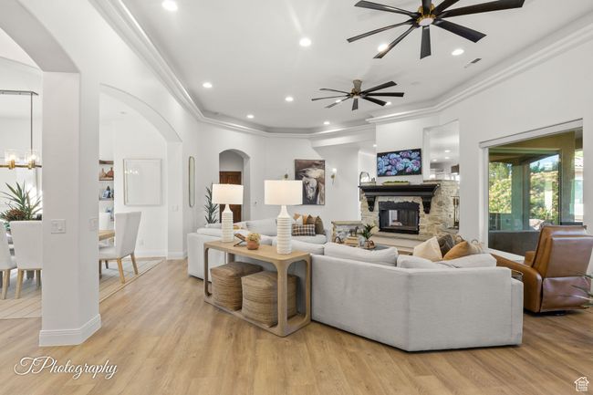 Living room featuring arched walkways, ceiling fan, crown molding, a stone fireplace, and recessed lighting | Image 24