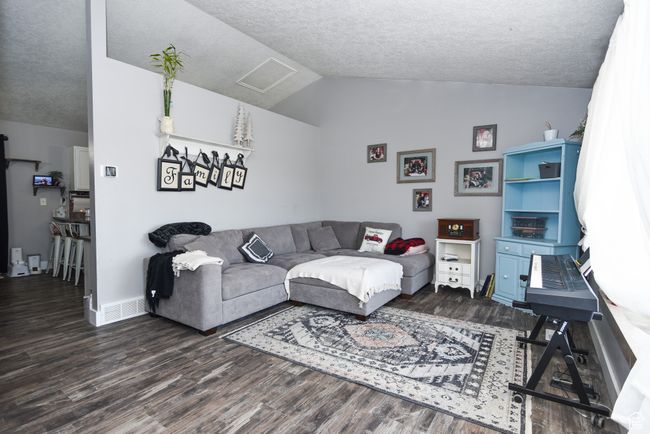Living area with baseboards, wood finished floors, a textured ceiling, and lofted ceiling | Image 9
