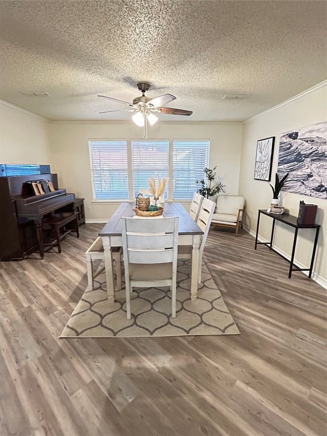 Dining room with a ceiling fan, a textured ceiling, wood finished floors, crown molding, and baseboards | Image 17