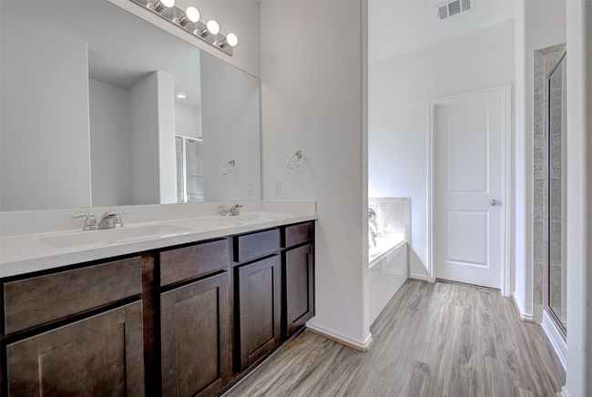 Full bath with wood finished floors, a shower stall, double vanity, a bath, and baseboards | Image 16