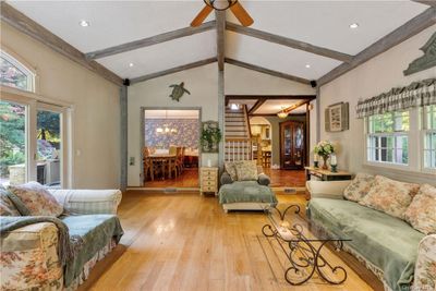 Living room featuring light hardwood / wood-style flooring, vaulted ceiling with beams, and ceiling fan with notable chandelier | Image 3