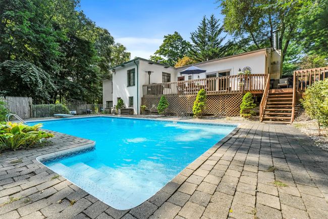 View of swimming pool with a wooden deck, a patio area, a fenced in pool, and fence | Image 43