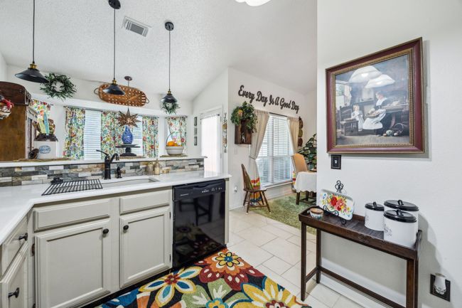 Kitchen with dishwasher, a textured ceiling, backsplash, light countertops, and light tile patterned floors | Image 13