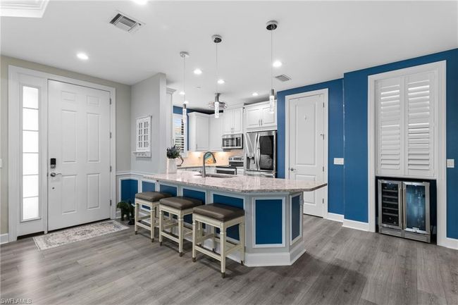 Kitchen with stainless steel appliances, wine cooler, wood finished floors, light stone counters, and recessed lighting | Image 5