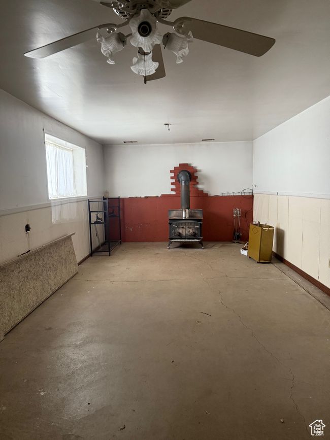 Interior space featuring a wood stove, unfinished concrete flooring, and ceiling fan | Image 23