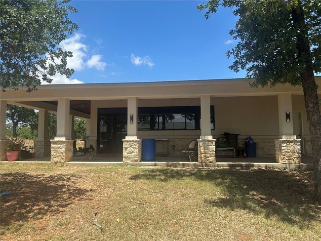 Back of house with stone siding, stucco siding, covered porch, and a lawn | Image 9