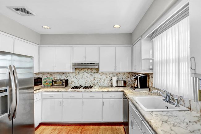 Kitchen featuring sink, white cabinets, stainless steel appliances, light hardwood / wood-style floors, and backsplash | Image 16