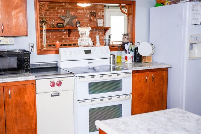 Kitchen featuring brown cabinets and white appliances | Image 7