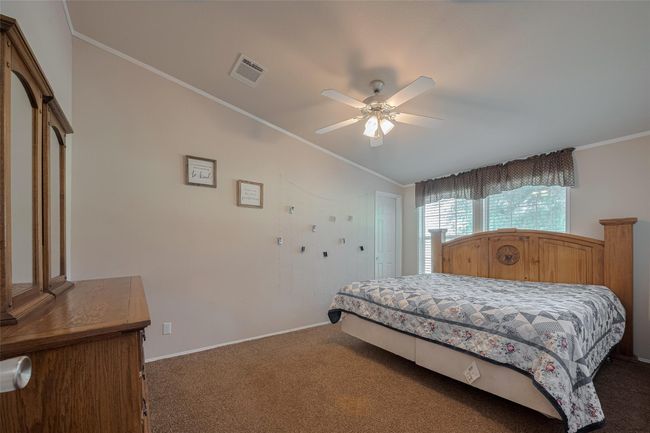 The room features a well-made bed adorned with decorative pillows and a stylish duvet cover, complemented by a hardwood floor that adds warmth to the space. | Image 20