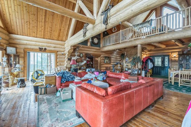 Living area with high vaulted ceiling, log walls, wood-type flooring, and wooden ceiling with exposed beams | Image 24