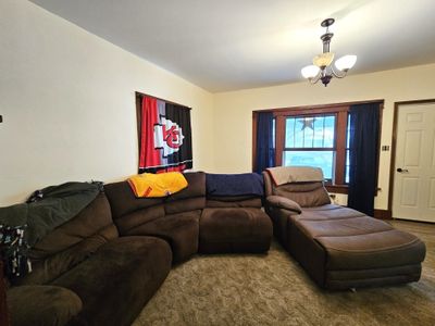 Living room with a chandelier and carpet floors | Image 3