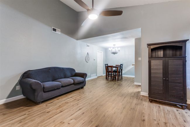 Living room with ceiling fan, high vaulted ceiling, light wood-style flooring, and a chandelier | Image 7