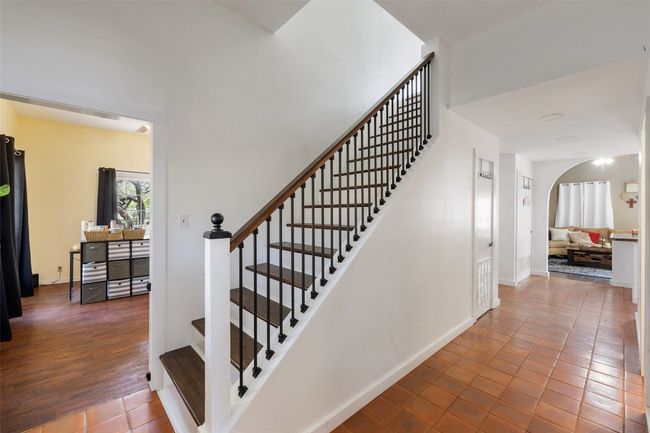 Staircase with tile patterned floors, baseboards, and arched walkways | Image 28