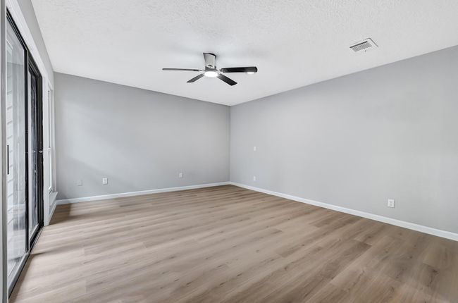 Spacious and serene primary bedroom featuring fresh paint, new luxury flooring, a modern ceiling fan, and sliding glass doors that provide abundant natural light and direct access to the private deck. A perfect retreat to unwind in comfort and style. | Image 24