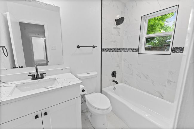 Full bathroom featuring toilet, vanity, bathtub / shower combination, and marble look tiles | Image 13