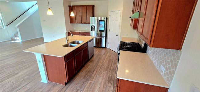 Kitchen featuring stainless steel appliances, range hood, light wood-style floors, and light countertops | Image 9