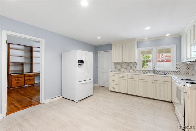Kitchen featuring light wood finished floors, a sink, white appliances, backsplash, and light countertops | Image 13