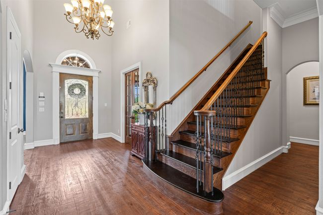 Entrance foyer with arched walkways, a high ceiling, and wood finished floors | Image 14