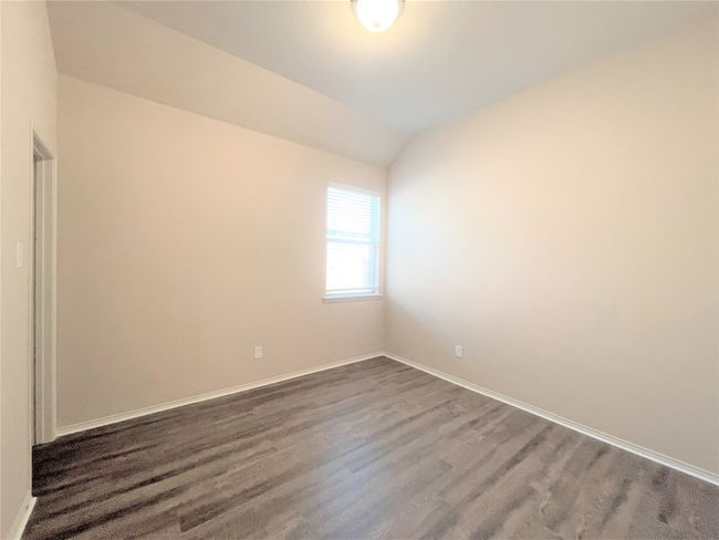 Empty room featuring dark wood-style floors and lofted ceiling | Image 15