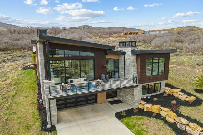 Back of house with a mountain view, driveway, stone siding, a garage, and a balcony | Image 70