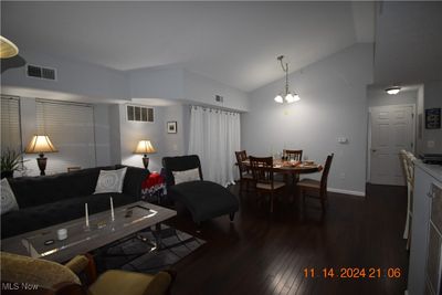 Living Room and Dining Room with dark hardwood / wood-style flooring, lofted ceiling, and an inviting chandelier | Image 3