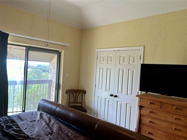 Bedroom with access to exterior, multiple windows, a textured wall, vaulted ceiling, and a closet | Image 14