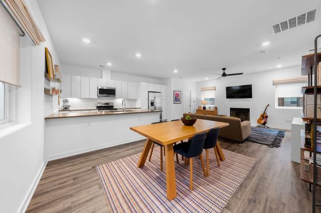 Dining space with a fireplace, wood finished floors, visible vents, ceiling fan, and recessed lighting | Image 11