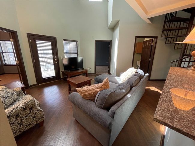 Living area featuring dark wood-type flooring, a towering ceiling, plenty of natural light, and baseboards | Image 6