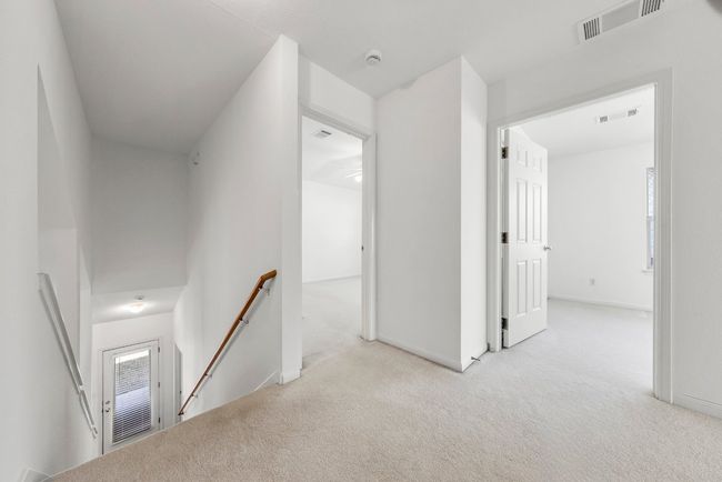 Hall with visible vents, an upstairs landing, carpet, and baseboards | Image 14
