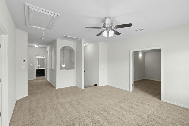 Empty room featuring attic access, carpet, a ceiling fan, and baseboards | Image 22