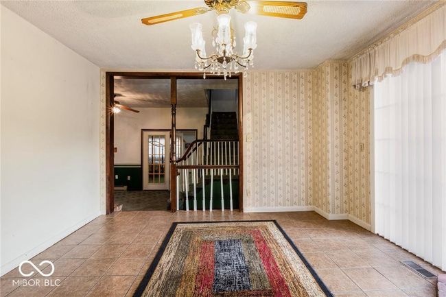 empty room featuring a ceiling fan, a chandelier, a textured ceiling, tile patterned flooring, and wallpapered walls | Image 7