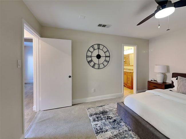 Bedroom with a ceiling fan, connected bathroom, light carpet, baseboards, and visible vents | Image 5