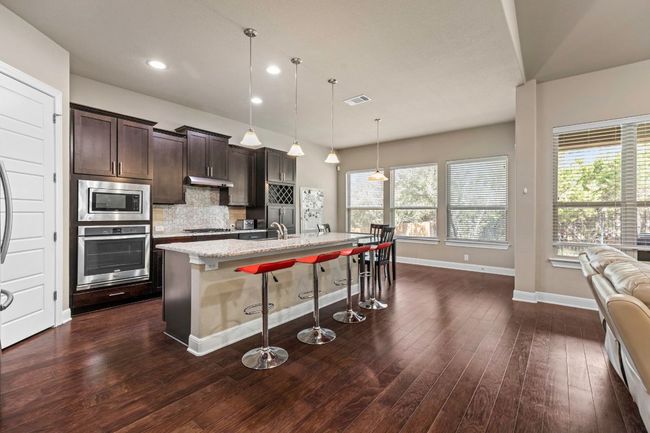 Kitchen with appliances with stainless steel finishes, a kitchen bar, healthy amount of natural light, an island with sink, and recessed lighting | Image 10