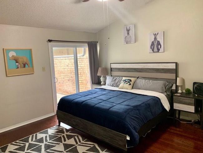 Bedroom with a textured ceiling, baseboards, wood finished floors, lofted ceiling, and ceiling fan | Image 9