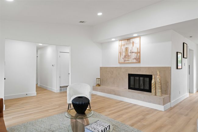 Living room featuring light wood finished floors, vaulted ceiling, recessed lighting, and a fireplace | Image 6