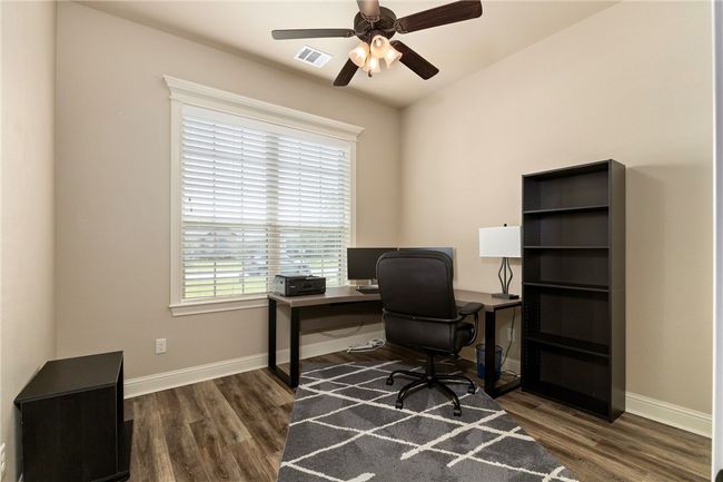 This home includes two secondary bedrooms, each featuring wood-finished floors, a ceiling fan, and a large window that fills the space with natural light, creating a bright and welcoming atmosphere. | Image 22
