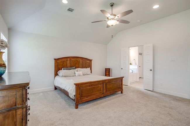 Bedroom featuring vaulted ceiling, light carpet, baseboards, ensuite bathroom, and recessed lighting | Image 20