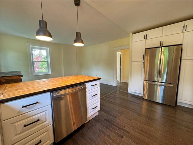 Kitchen with dark hardwood / wood-style flooring, pendant lighting, wood counters, appliances with stainless steel finishes, and white cabinetry | Image 5