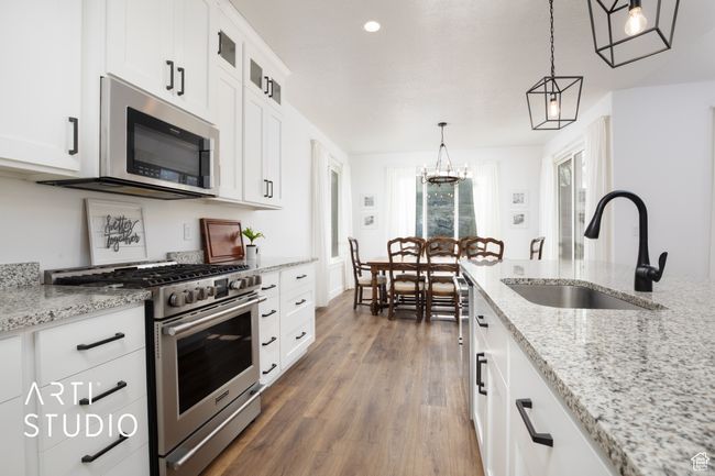 Kitchen with sink, decorative light fixtures, stainless steel appliances, and white cabinets | Image 12
