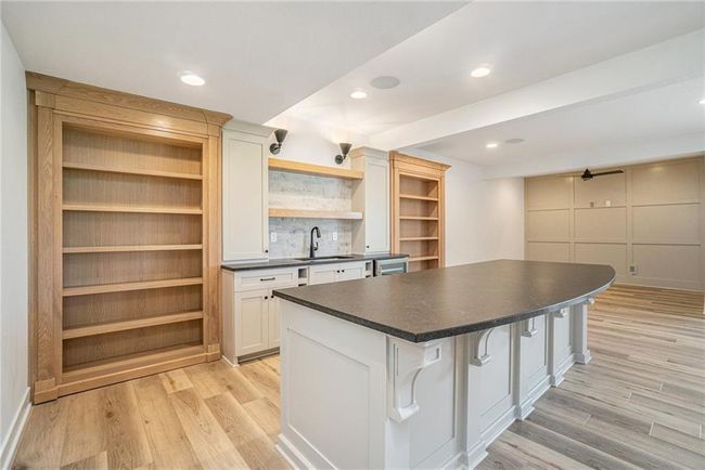 Kitchen with open shelves, a sink, dark countertops, light wood-style floors, and a center island | Image 45