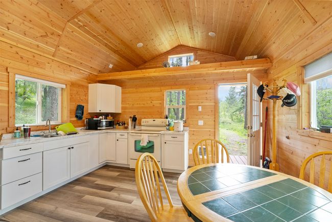 Kitchen featuring white electric stove, vaulted ceiling, stainless steel microwave, healthy amount of natural light, and wood walls | Image 8