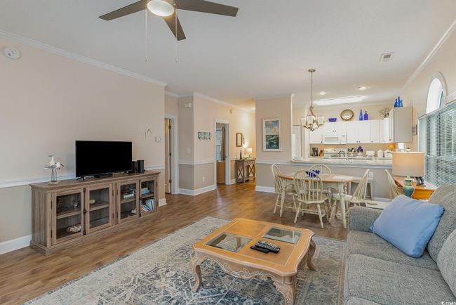 Living room featuring wood-type flooring, ceiling fan with notable chandelier, and crown molding | Image 5