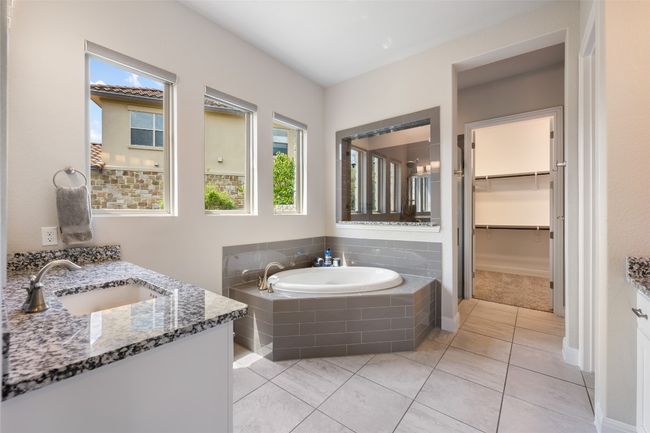 Bathroom featuring vanity, healthy amount of natural light, a garden tub, and tile patterned flooring | Image 19