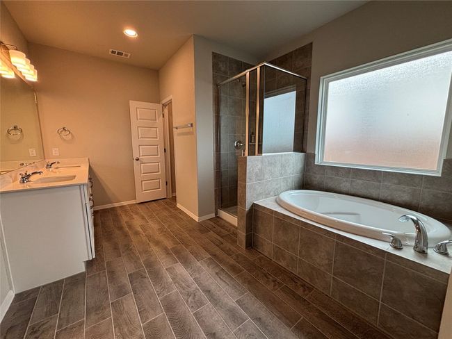 Bathroom featuring a garden tub, double vanity, a stall shower, and wood finished floors | Image 16