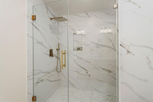 The primary ensuite bathroom offers a luxurious framless glass shower with floor to ceiling porcelain tile surround. This relaxing shower offers an elegant rainfall showerhead with a separate high-powered detachable shower wand. | Image 22