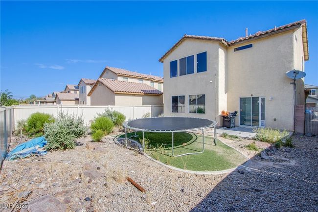 Rear view of house featuring a trampoline, a fenced backyard, stucco siding, and a tile roof | Image 21
