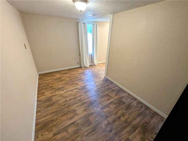 Empty room featuring dark wood finished floors, a textured ceiling, and baseboards | Image 16