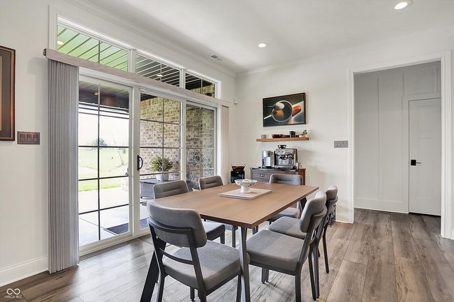 dining space with wood finished floors, a healthy amount of sunlight, crown molding, and baseboards | Image 22