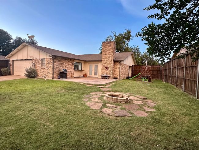 Rear view of property with french doors, a fire pit, a chimney, brick siding, and a fenced backyard | Image 40